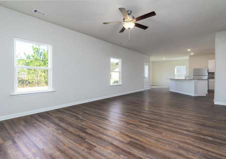 Spacious family room with a ceiling fan, wood-style flooring, and windows.