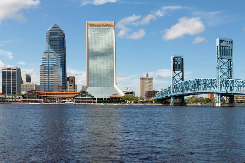 Jacksonville, Florida cityscape showing downtown skyscrapers, blue steel bride crossing St. Johns River, and calm dark waters