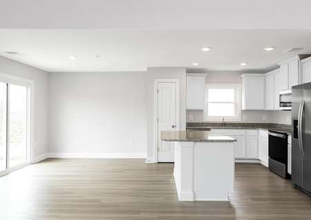 Photo of an open dining area and kitchen with plank flooring, white cabinets, granite counters and stainless appliances.