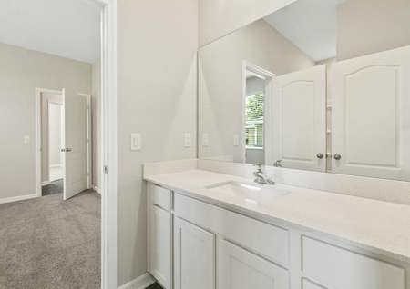 Full bathroom with a large vanity connected to a spacious bedroom. 