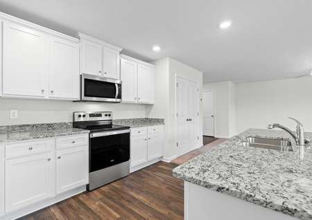 Kitchen with stainless steel appliances, granite countertops, white cabinets and vinyl flooring.