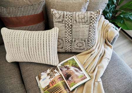 Staged couch with open book, pillows and blanket.