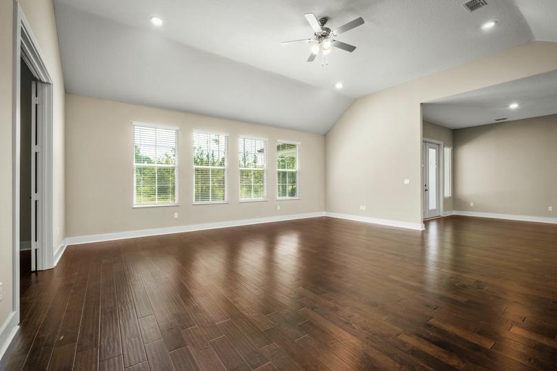 Living room with wood floor, lots of windows and a ceiling fan.