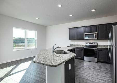 Open-concept kitchen with installed stainless steel appliances and granite countertops.