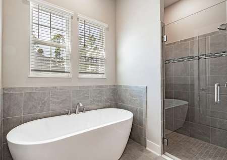 Master bathroom with a standalone tub, walk-in shower, tile floors and two windows. 