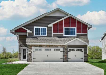 Front elevation photo of the two-story St. Benedict by LGI Homes with a three-car garage and red, taupe and cream siding with white trim.