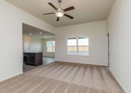 Blanco great room with brown carpets, access to the kitchen and dining area, and overhead ceiling fan with light