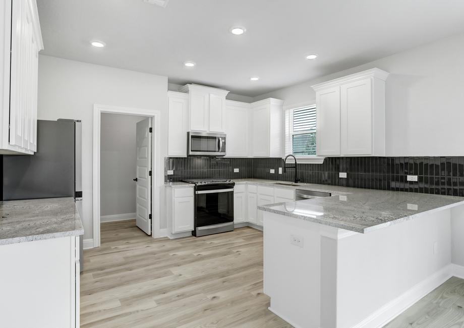 Chef-ready kitchen with stainless appliances, white cabinetry with crown molding, and recessed lighting.