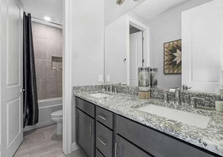 Mead bathroom with two sinks, granite countertop, and private toilet/bath room