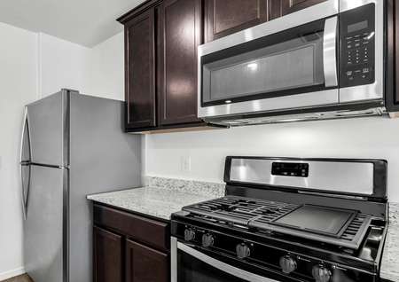 Designer kitchen with a gas stovetop, stainless steel appliances, and granite countertops. 