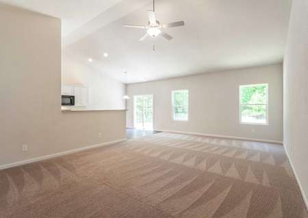 Alexander great room with brown carpet, vaulted ceilings, and white trim