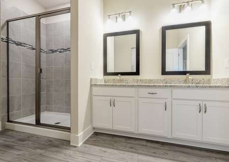 Double sinks, granite countertops and a step-in shower are located in the full bathroom of the owner's retreat.