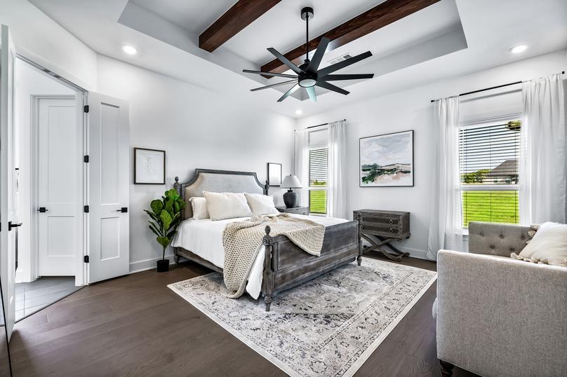 Expansive master bedroom with two windows and a ceiling fan.
