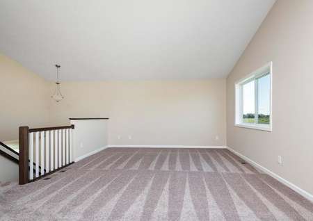 Spacious family room with carpet, vaulted ceilings, a window overlooking the back yard.