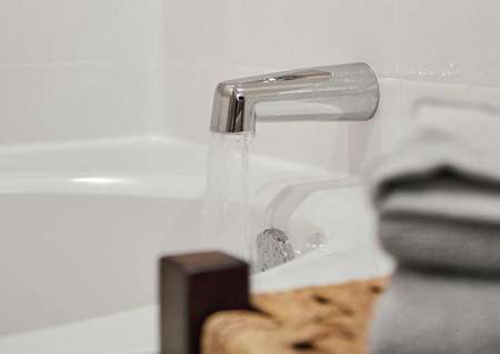 Bath tub spout with water running.