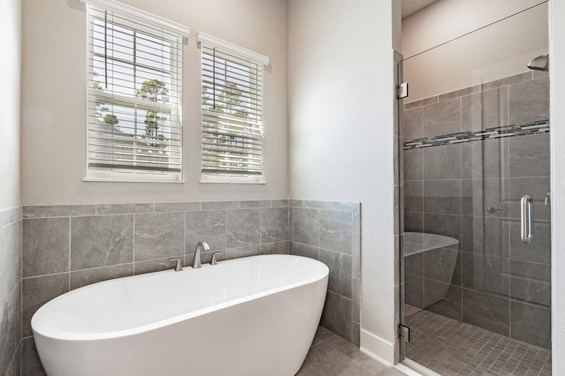 Master bathroom with a standalone tub, walk-in shower, tile floors and two windows.