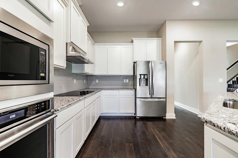 Kitchen with stainless appliances, granite countertops, white cabinetry and wood floors.