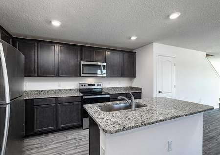 Kitchen comprised of granite countertops, stainless steel appliances, upper-wood cabinets and vinyl wood floors. 