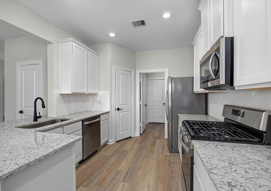 The kitchen has white cabinets and stainless steel appliances.