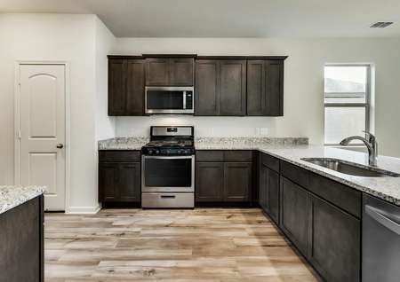 The Maple has sprawling granite countertops, brown cabinetry and light flooring.