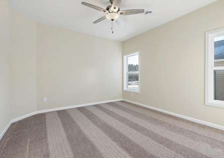 Photo of master bedroom with carpet and ceiling fan and two windows along side of home.