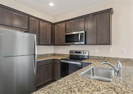 The kitchen comes with stainless steel appliances, tan granite and brown cabinetry.