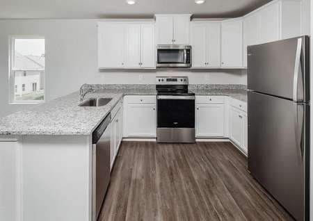 Stainless steel appliances, white cabinets with hardware and granite countertops.