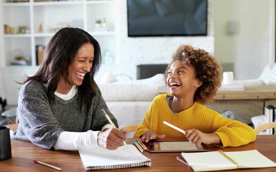 Mother and daughter laughing together while doing homework.