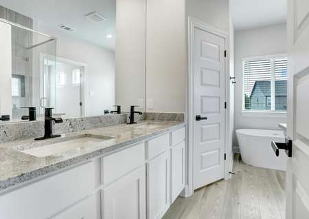 Master bathroom with granite countertops, white cabinets, and a soaking tub.