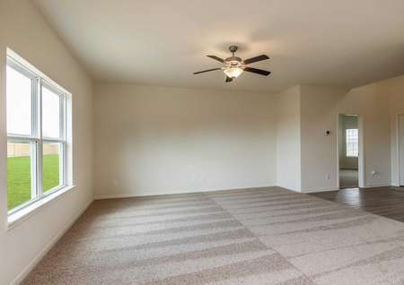 Cypress family room with brown ceiling fan with light fixture, large backyard window, and light colored brown carpet