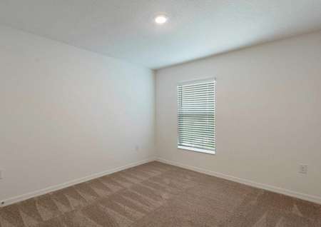 Carpeted spare room in the Cocoa floor plan with brown carpet flooring, white walls and a single hung window covered by blinds.