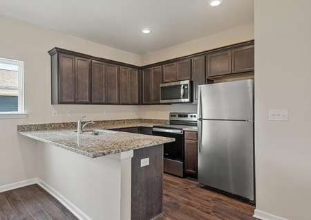The spacious kitchen has stainless steel appliances and brown cabinetry.