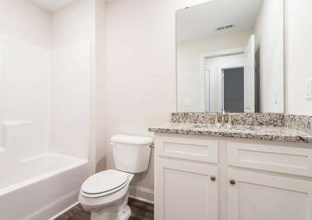 Secondary bathroom with white vanity, granite countertops and vinyl flooring.