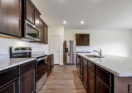Rio kitchen with wood flooring, light colored ceramic countertops, and stainless steel oven, stove, and microwave