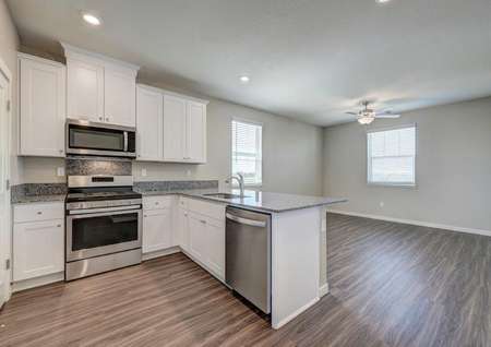 The kitchen in the Crystal floor plan with stainless steel appliances, granite countertops and wood-like flooring.