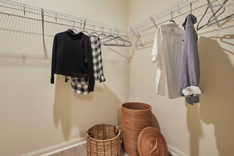 Staged closet with shirts on hangers and two woven baskets.
