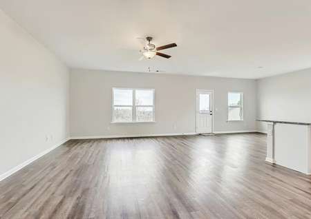 Spacious family room with wood-style flooring throughout, a ceiling fan, and windows.