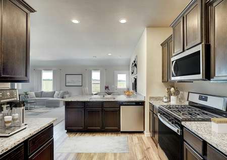 Staged kitchen with brown cabinetry and stainless steel appliances.