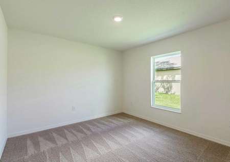 A single hung window and a ceiling light fixture in the carpeted spare bedroom of the Cocoa floor plan.